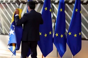 Un miembro del protocolo coloca las banderas de la Unión Europea y de otros países antes de la llegada de los participantes a la cumbre de la UE, el jueves 23 de junio de 2022, en Bruselas. (AP Foto/Olivier Matthys)