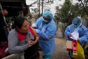 Marlith Fasabi recibe la dosis de la vacuna contra la gripe y la vacuna Moderna contra el COVID-19 durante una campaña de inoculación puerta a puerta en el barrio Ticlio Chico, en las afueras de Lima, Perú, en el primer día oficial de invierno, el martes 21 de junio de 2022. (Foto AP/Martín Mejía)