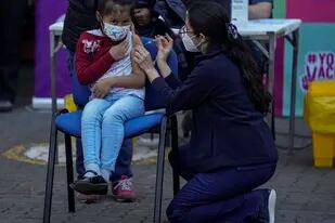Un trabajador de la salud inocula a una niña contra el COVID-19 en la escuela Providencia en Santiago, Chile, el lunes 27 de septiembre de 2021, durante el inicio de la vacunación en escuelas para niños de 6 a 11 años