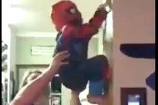 Entre las risas de los presentes, el pequeño Spiderman va trepando ayudado por su papá