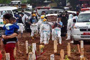 Trabajadores funerarios trasladan víctimas fallecidas de coronavirus en el cementerio público de Pedurenan en Bekasi, Java Occidental, Indonesia