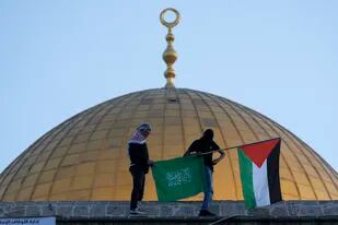 En esta imagen de archivo, dos palestinos enmascarados, con una bandera palestina y otras de Hamas, durante las celebraciones del Eid al-Fitr, cerca de la cúpula de la mezquita Al-Aqsa, en la Ciudad Vieja de Jerusalén, el 2 de mayo de 2022. (AP Foto/Mahmoud Illean, archivo)
