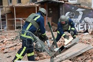 Rescatistas ucranianos acceden a los escombros para despejar en un edificio residencial, parcialmente destruido tras un ataque con misiles en Kharkiv el 30 de enero de 2023, en medio de la invasión rusa de Ucrania
