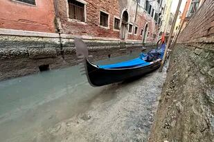 Una góndola está atracada en un canal seco durante la marea baja en Venecia, Italia, el lunes 20 de febrero de 2023