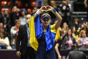 La ucraniana Dayana Yastremska, envuelta en la bandera nacional de su país, saluda al público que la alentó en el torneo de Lyon