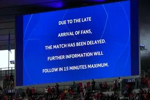 La pantalla gigante del Stade de France anuncia la demora en el inicio de la final de la Liga de Campeones entre el Liverpool y el Real Madrid, el sábado 28 de mayo de 2022 (AP Foto/Christophe Ena)