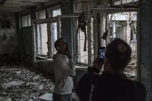 Un turista posa para la foto en una escuela destruida por el paso del tiempo