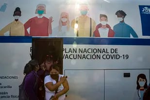 Mujeres salen de un autobús que se usa para inyectar la vacuna contra COVID-19 en Santiago, Chile.