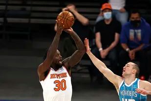 Julius Randle de los Knicks de Nueva York va por el triple mientras lo defiende Cody Zeller de los Hornets de Charlotte en el encuentro del sábado 15 de mayo del 2021. (Elsa/Pool Photo via AP)