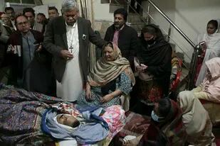 Familiares del padre William Siraj, asesinado en Pakistán, junto con su cadáver en Peshawar, Pakistán el 30 de enero de 2022. (Foto AP/Muhammad Sajjad)