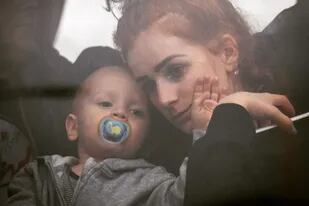 Una mujer sostiene a su bebé dentro de un autobús cuando salen de Kiev, Ucrania, el jueves 24 de febrero de 2022