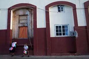Los estudiantes esperan al otro lado de la calle de su escuela pública mientras el alumnado ingresa en grupos para su primer día de clases presenciales después de dos años de aprendizaje en línea en casa debido a la pandemia de COVID-19 en Ciudad de Panamá, el lunes  7 de marzo de 2022. (AP Foto/Arnulfo Franco)