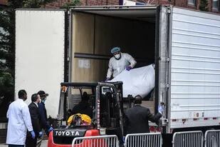 En plena crisis por el avance del coronavirus, los trabajadores sanitarios llevan un cuerpo a un camión refrigerado afuera del Hospital de Brooklyn