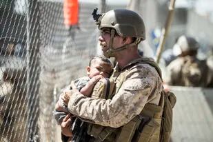 En esta imagen suministrada por el Cuerpo de Infantería de Marina de EEUU, un efectivo carga a un bebé durante las operaciones de evacuación en el Aeropuerto Internacional Hamid Karzai en Kabul, Afganistán, el jueves 26 de agosto de 2021. (Sgt. Samuel Ruiz/U.S. Marine Corps vía AP)