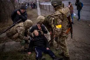 Una mujer es atendida por soldados ucranianos luego de cruzar el río Irpin luego de escapar en las afueras de Kiev