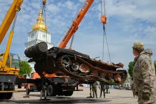 Soldados ucranianos descargan un tanque ruso destruido para instalarlo como símbolo de guerra en el centro de Kiev, Ucrania, el viernes 20 de mayo de 2022. La catedral de San Miguel está al fondo. (Foto AP/Efrem Lukatsky)