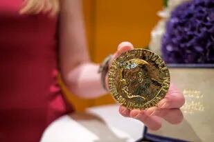 Una empleada sostiene la medalla del Premio Nobel de la Paz del periodista ruso Dmitry Muratov de 23 quilates antes de que sea subastada en Times Center el lunes 20 de junio de 2022 en Nueva York. (AP Photo/Eduardo Munoz Alvarez)