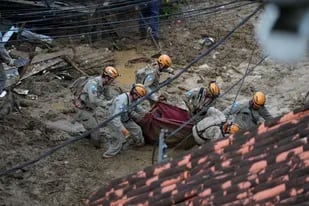 Rescue workers carry the body of a landslide victim in Petropolis, Brazil, Wednesday, Feb. 16, 2022. Extremely heavy rains set off mudslides and floods in a mountainous region of Rio de Janeiro state, killing multiple people, authorities reported. (AP Photo/Silvia Izquierdo)