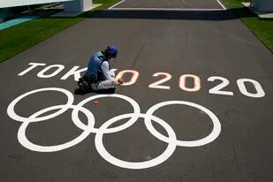 Un empleado pinta los anillos olímpicos en una pista de los Juegos Olímpicos de Tokio.
