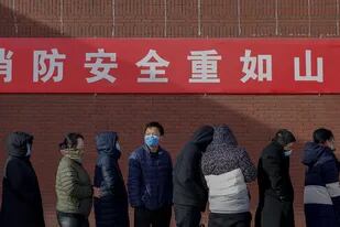 Los residentes con mascarillas esperan en la fila para hacerse el hisopado en Pekín, el 29 de diciembre 2020