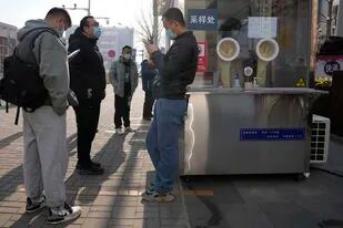 Trabajadores y residentes esperan cerca de un puesto de pruebas de detección del coronavirus, en Beijing, China, el 18 de enero de 2022. (AP Foto/Ng Han Guan)