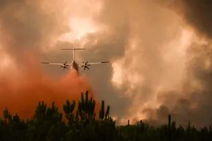 Un avión de extinción de incendios rocía retardante de fuego sobre los árboles durante un incendio forestal cerca de Belin-Beliet en Gironde, suroeste de Francia, el 10 de agosto de 2022.