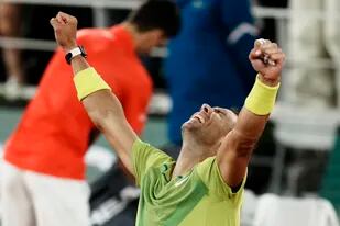 El final en París: Rafael Nadal alza sus brazos luego de una victoria épica; detrás, el campeón saliente de Roland Garros, Novak Djokovic guarda sus raquetas tras la derrota y la eliminación.