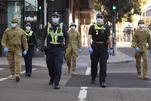 Un grupo de policías y soldados patrullan el área de Docklands en Melbourne el 2 de agosto de 2020, después del anuncio de nuevas restricciones para frenar la propagación del coronavirus