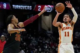 Trae Young, de los Hawks de Atlanta, dispara frente a Isaac Okoro, de los Cavaliers de Cleveland, durante la segunda mitad del partido de la NBA disputado el viernes 31 de diciembre de 2021 (AP Foto/Tony Dejak)