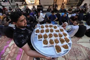 Un voluntario sirve comida para la comida Iftar (ruptura del ayuno) en Kadhimiya durante el mes sagrado del Ramadán, en Irak