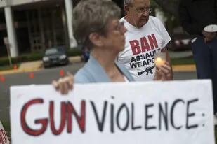 Una manifestante sostiene un cartel que exige el fin de la violencia con armas