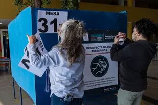 Empeados del servicio electoral instalan las mesas para de votación en una escuela de Santiago
