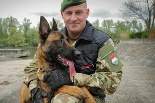 El sargento Balazs Nemeth posa con su perro rastreador de bombas, Logan, en la guarnición de Eliminación de Artefactos Explosivos de las Fuerzas Húngaras en Budapest, Hungría, el 28 de abril de 2022. (AP Foto/Bela Szandelszky)