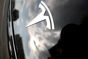 Archivo - Fotografía del 8 de julio de 2018 de nubes reflejadas sobre el logotipo de Tesla en el capó de un vehículo de la marca afuera de una sala de exposición en Littleton, Colorado. (AP Foto/David Zalubowski, Archivo)