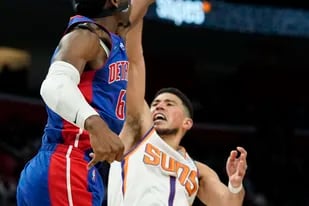 El base de los Pistons de Detroit Hamidou Diallo bloquea el tiro del base de los Suns de Phoenix Devin Booker durante el encuentro del domingo 16 de enero del 2022. (AP Foto/Carlos Osorio)