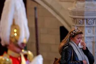 Una mujer se suena la nariz mientras la gente pasa a presentar sus respetos frente al ataúd de la reina Isabel II en el Salón Westminster, en el Palacio de Westminster, el domingo 18 de septiembre de 2022, en Londres. (Adrian Dennis/Fotos compartidas vía AP)