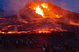 Las figuras de las personas están iluminadas por el resplandor de la lava