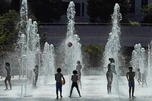 Un grupo de niños juega en una fuente de agua en París , en medio de una ola de calor que afecta a Europa