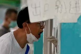 Un hombre pasa una prueba rutinaria de COVID-19 en un centro de pruebas en Beijing, el domingo 7 de agosto de 2022. (AP Foto/Andy Wong)