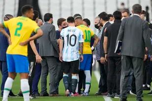 Lionel Messi y Neymar charlan con un agente sanitario luego que el partido entre Argentina y Brasil por las eliminatorias del Mundial fue interrumpido, el domingo 5 de septiembre de 2021. (AP Foto/Andre Penner)