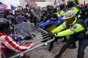 ARCHIVO - Partidarios violentos de Donald Trump tratan de rebasar una barrera policial en el Capitolio en Washington el 6 de enero del 2021.  (AP Foto/John Minchillo)