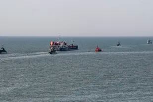 Un barco ruso, al centro, escoltado por botes militares rusos, sale del puerto de Mariúpol, en territorio controlado por la República Popular de Donetsk, en el este de Ucrania, el martes 31 de mayo de 2022. (AP Foto)