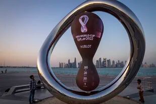 Un par de niños observa el reloj que marca la cuenta regresiva hacia el Mundial de Qatar en Doha, el 22 de noviembre de 2021 (AP Foto/Darko Bandic, archivo)