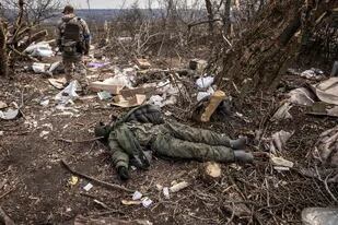 Un soldado ucraniano pasa junto al cuerpo de un soldado ruso tirado en el suelo después de que las tropas ucranianas retomaran la aldea de Mala Rogan, al este de Kharkiv, el 30 de marzo de 2022