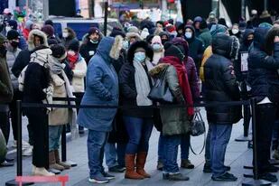 Varias personas esperan en una fila para realizarse a una prueba de COVID-19 en Times Square, Nueva York, el lunes 20 de diciembre de 2021. (AP Foto/Seth Wenig)