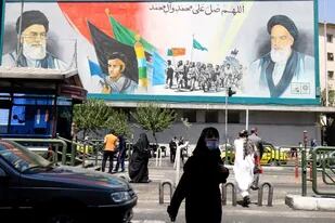 Iraníes caminan junto a un cartel del ayatollah Ali Khamenei (izquierda) y el líder de la Revolución Islámica, Ruhollah Khomeini (derecha) (ATTA KENARE / AFP)