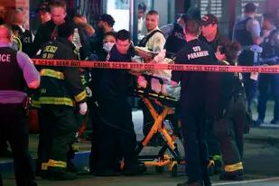 Personal de emergencias traslada a una persona herida en un tiroteo a una ambulancia el sábado 14 de mayo de 2022, en el centro de Chicago. (Terrence Antonio James/Chicago Tribune vía AP)