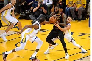 Un símbolo: LeBron James rodeado por el "big three" de Golden State. Con infracción, Kevin Durant y Stephen Curry intentan robarle la pelota al astro de Cleveland, mientras Klay Thompson es testigo.