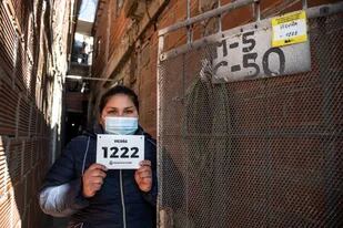 Una mujer residente en la villa 31 muestra el cartel de denominación de la calle y el número donde se ubica su vivienda