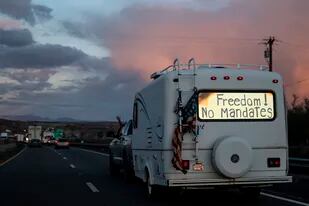 ARCHIVO - Una camioneta con la frase "¡Libertad! ¡No mandatos" en su ventana trasera viaja como parte de una caravana rumbo a Washington D.C. para protestar contra los mandatos por el COVID-19, el 23 de febrero de 2022, cerca de Needles, California. (AP Foto/Nathan Howard, archivo)